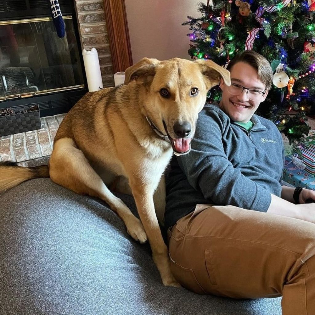 A person and dog sitting on a couch Description automatically generated