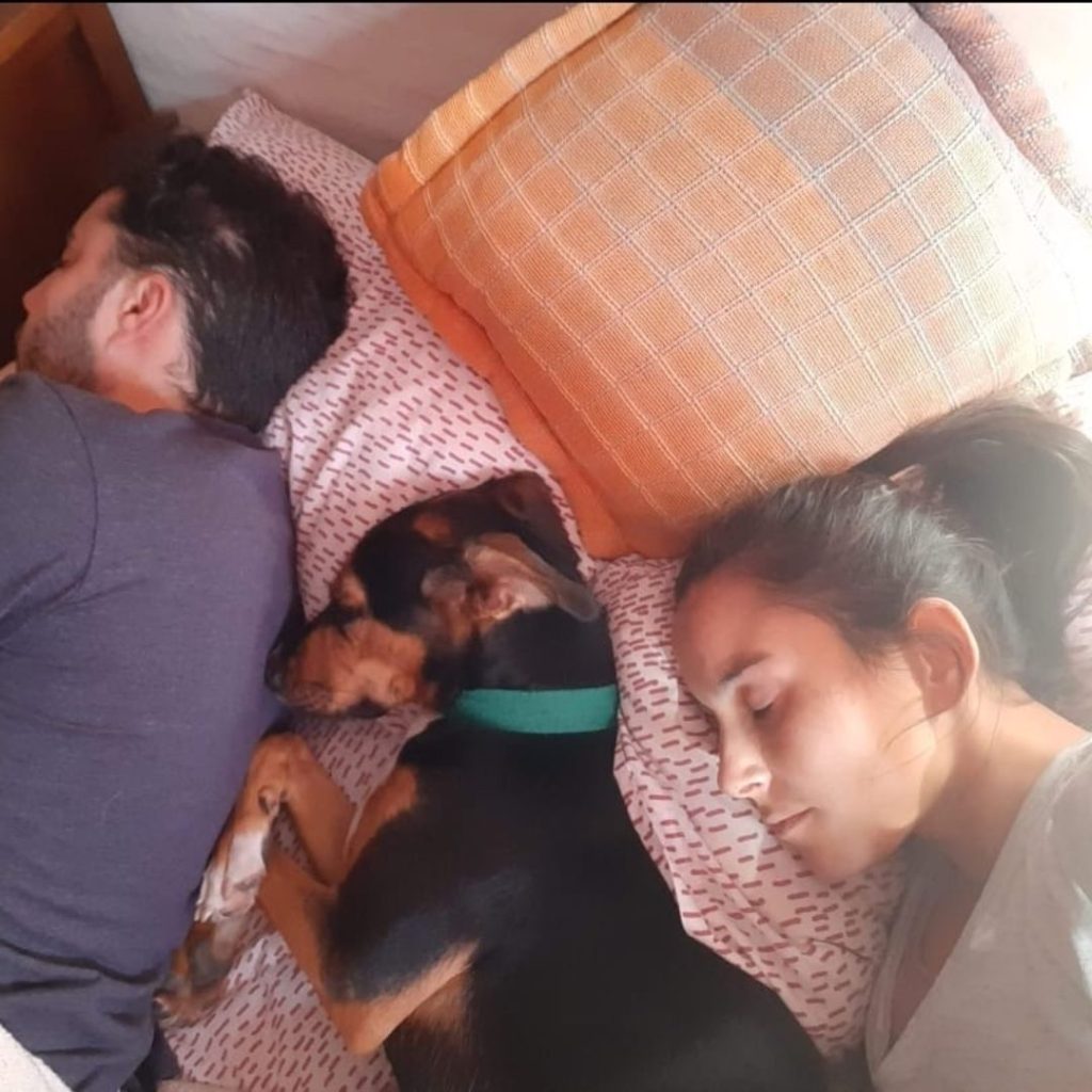 A person and person sleeping with a dog Description automatically generated