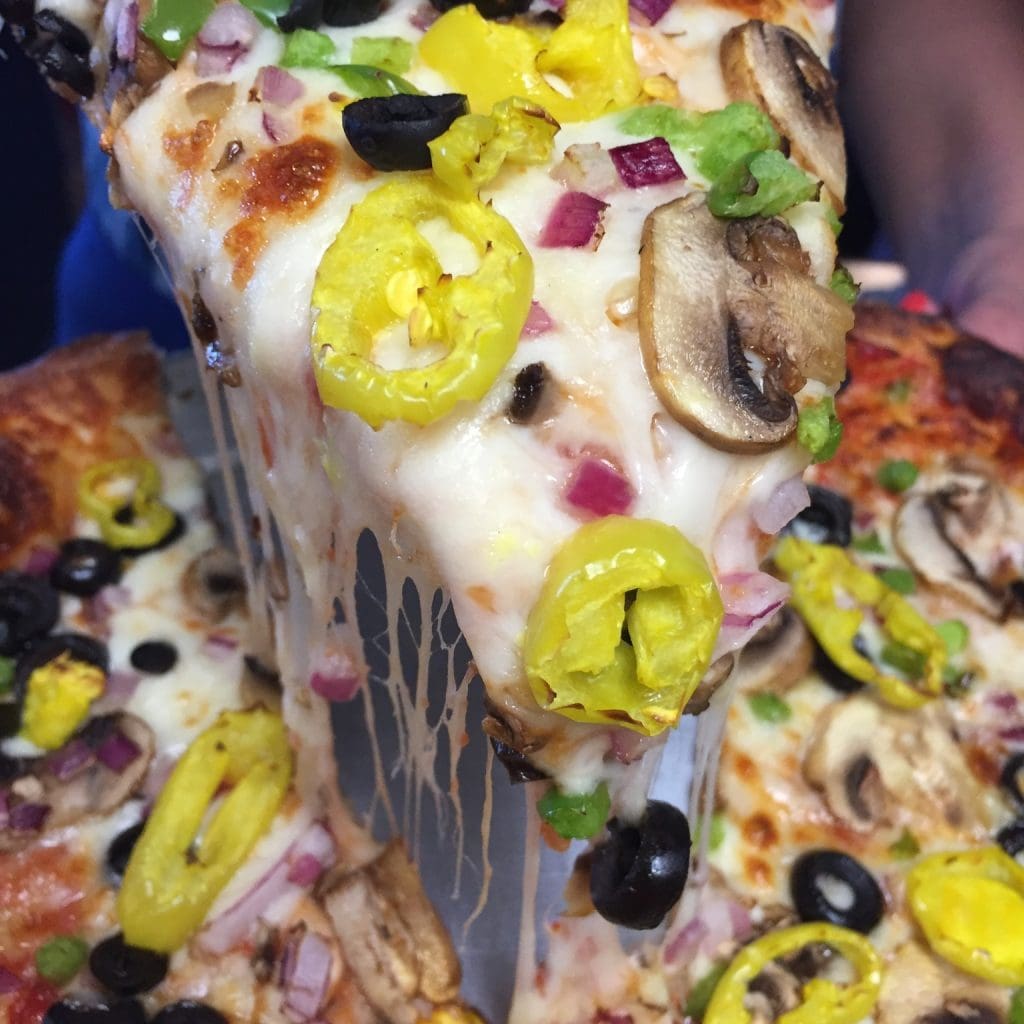 A slice of pizza with vegetables

Description automatically generated